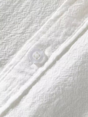 White men's button-up shirt with textured fabric and a single visible button.
