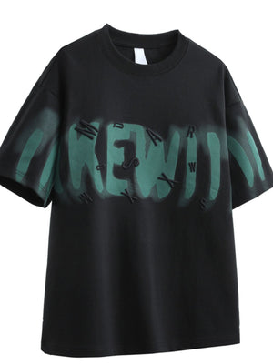 Black oversized graphic t-shirt with green spray paint effect and raised lettering.
