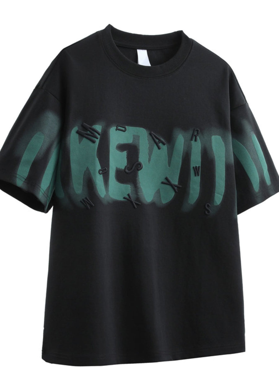 Black oversized graphic t-shirt with green spray paint effect and raised lettering.