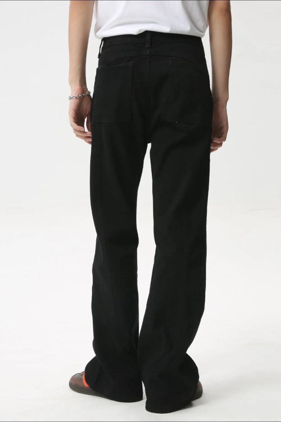 Black denim jeans with flare leg and panel seams, shown from the back.