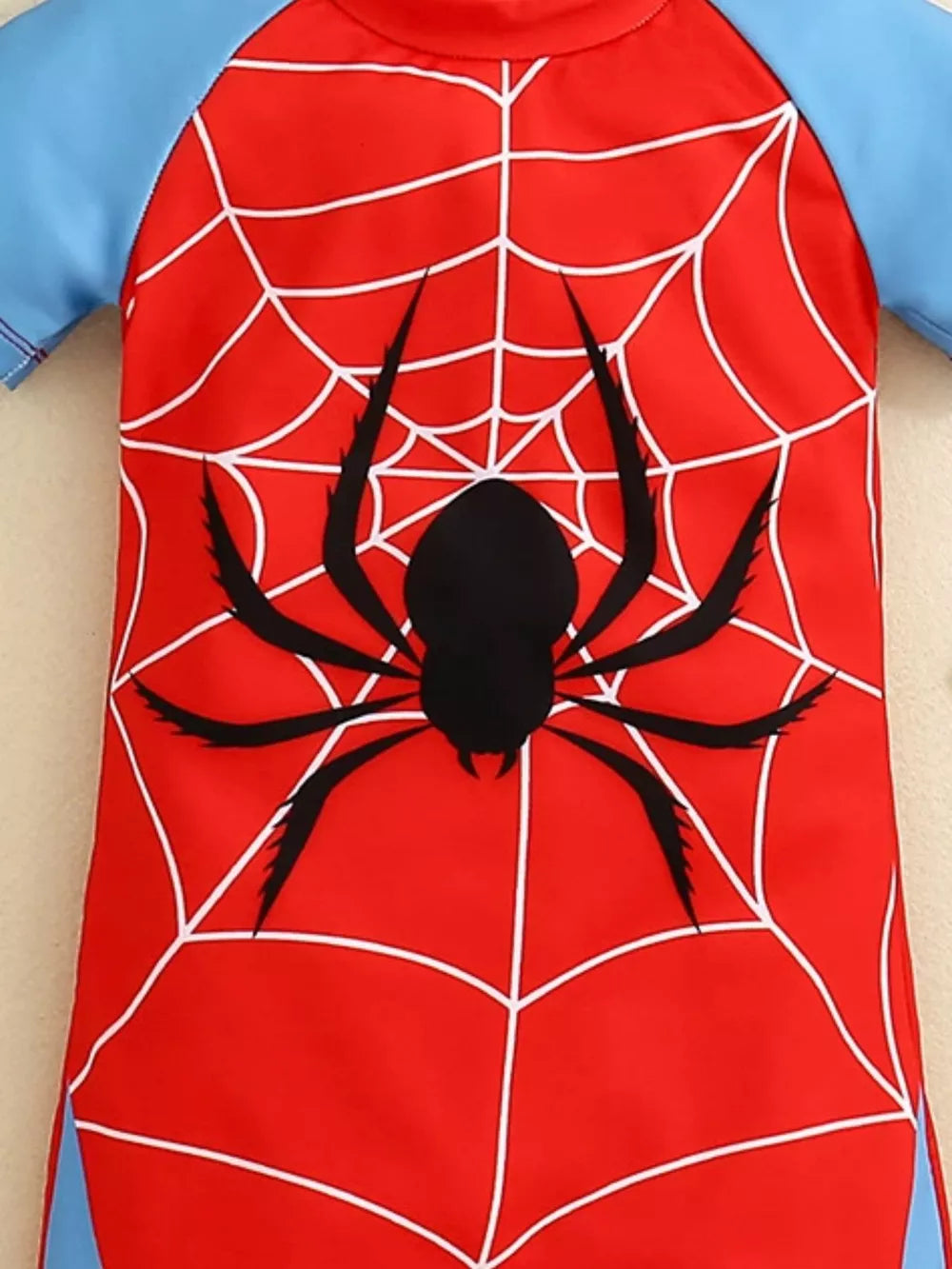 Toddler one-piece swimsuit in red with white spiderweb and black spider graphic, blue sleeves.