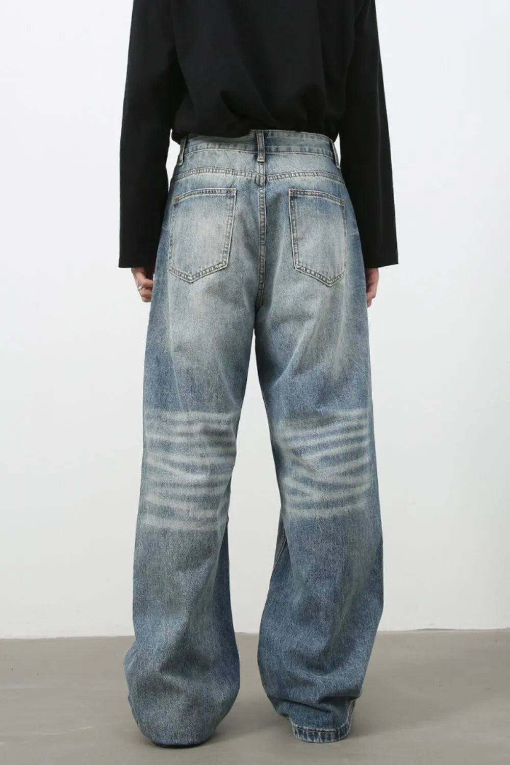 Baggy wash denim trousers in medium blue with horizontal faded stripes on the legs.