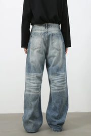 Baggy wash denim trousers in medium blue with horizontal faded stripes on the legs.