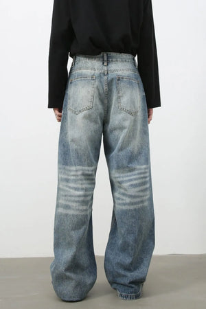 Baggy wash denim trousers in medium blue with horizontal faded stripes on the legs.