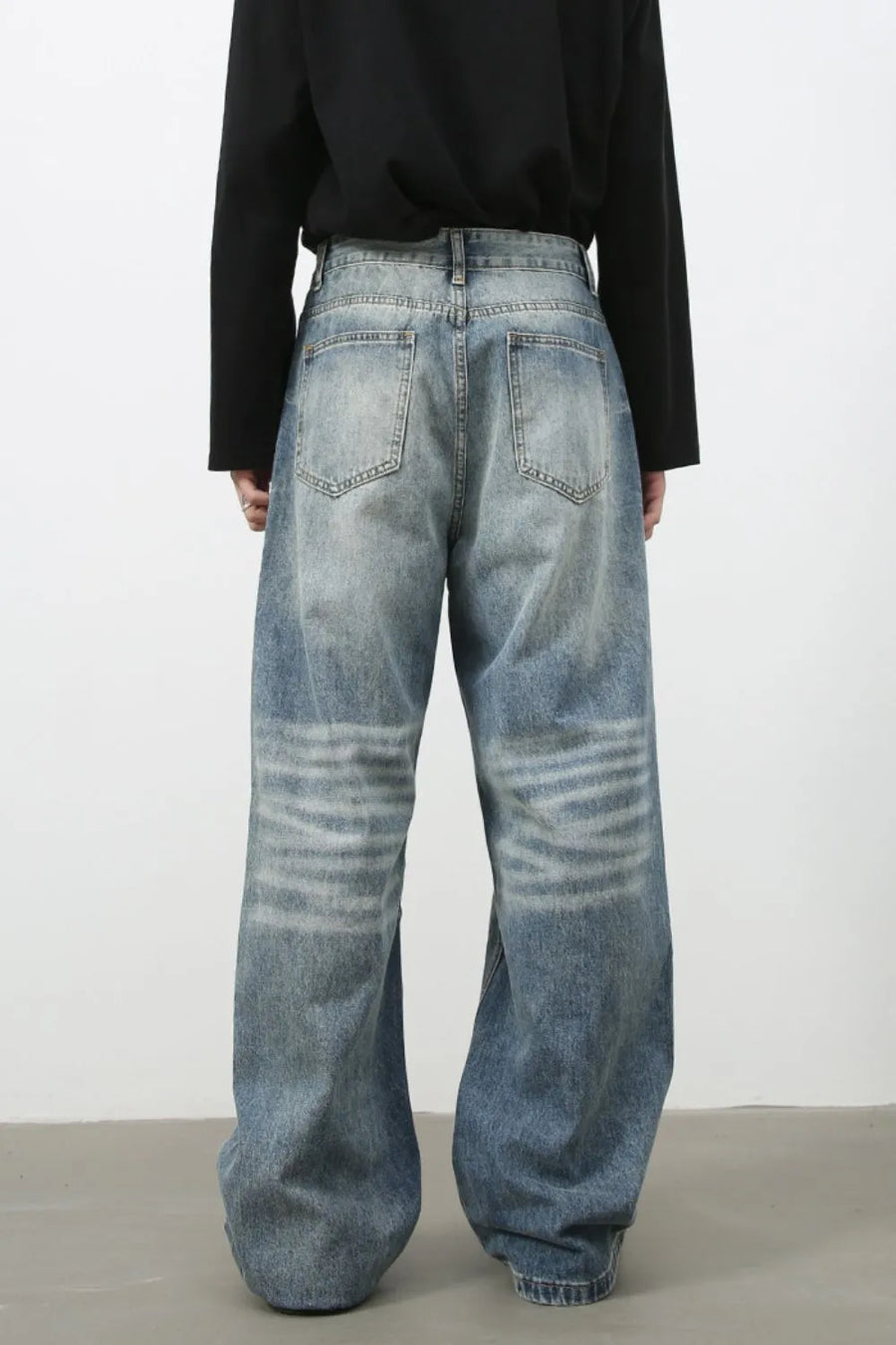 Baggy wash denim trousers in medium blue with horizontal faded stripes on the legs.