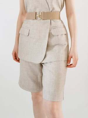 Caramel elastic waist belt with gold sculpted buckle, styled with linen shorts.