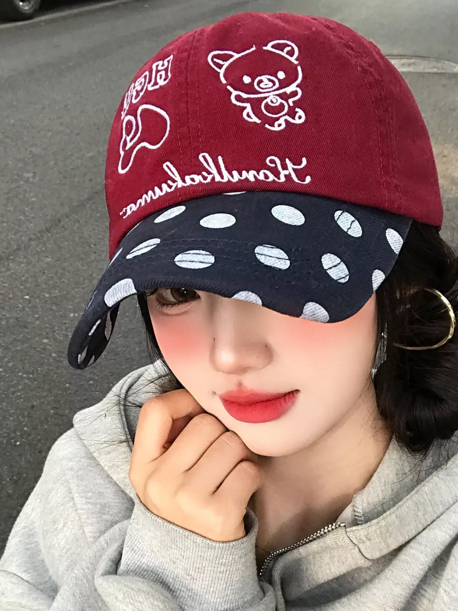 Baseball cap with red crown and white bear embroidery, navy brim with white polka dots.