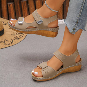 Apricot adjustable wedge sandals with hook-and-loop straps and a wooden-look sole.
