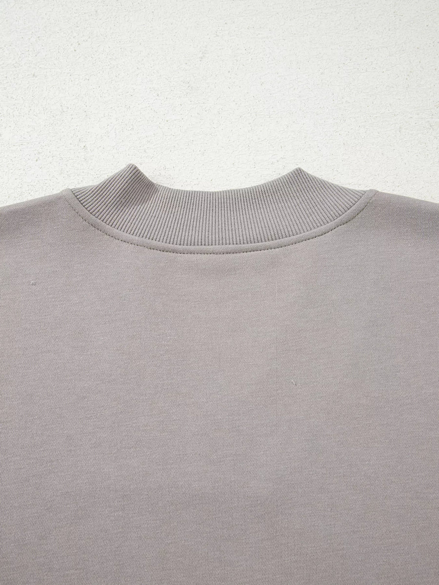 Gray sweatshirt with ribbed mock neck detail and embroidered Aztec pattern.