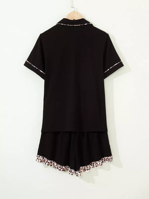Black button-up pajama set with short sleeves and leopard trim on collar, cuffs, and shorts.