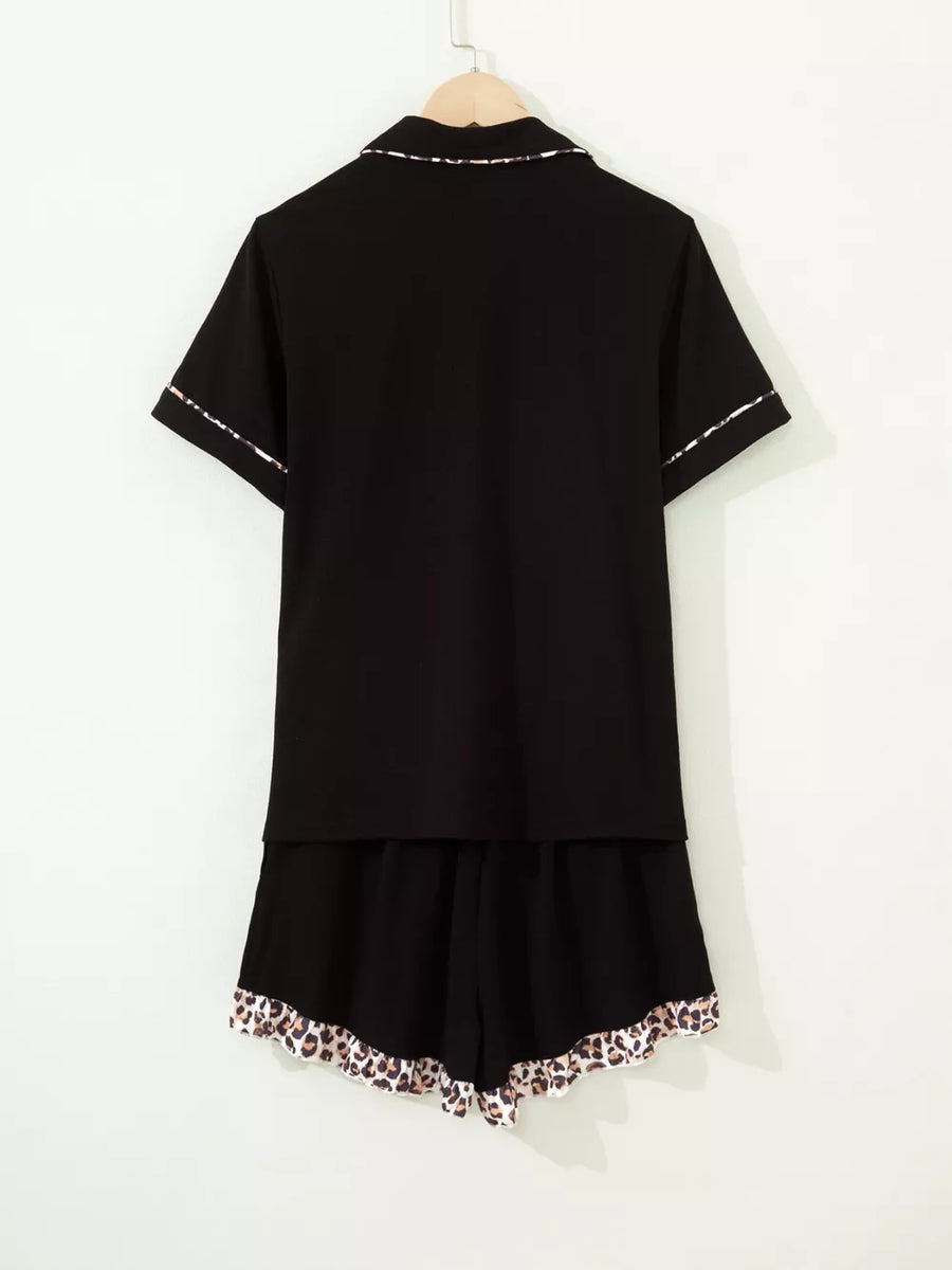 Black button-up pajama set with short sleeves and leopard trim on collar, cuffs, and shorts.