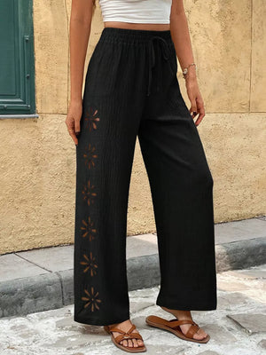Black wide-leg pants with drawstring waist and floral cutouts on the side.