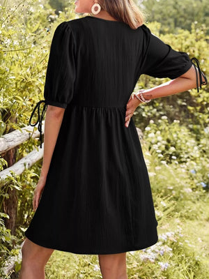 Black mini dress with puff sleeves and tie details, cinched waist, v-neck