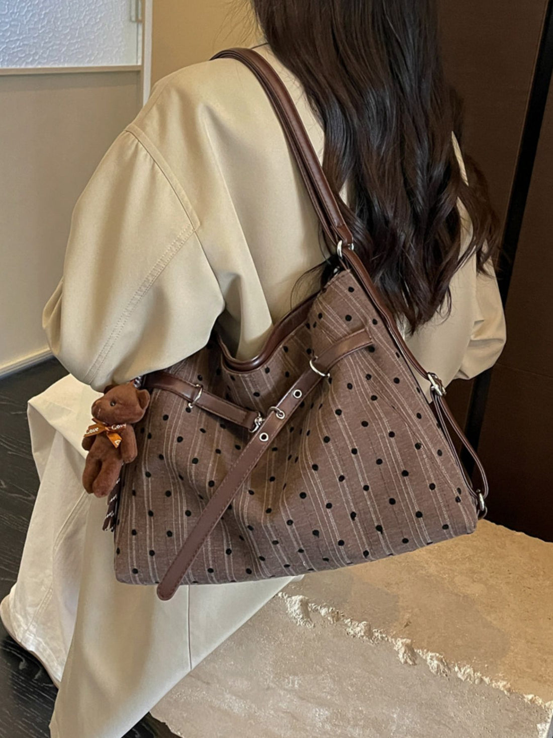 brown handbag featuring buckle straps and polka dot, striped
