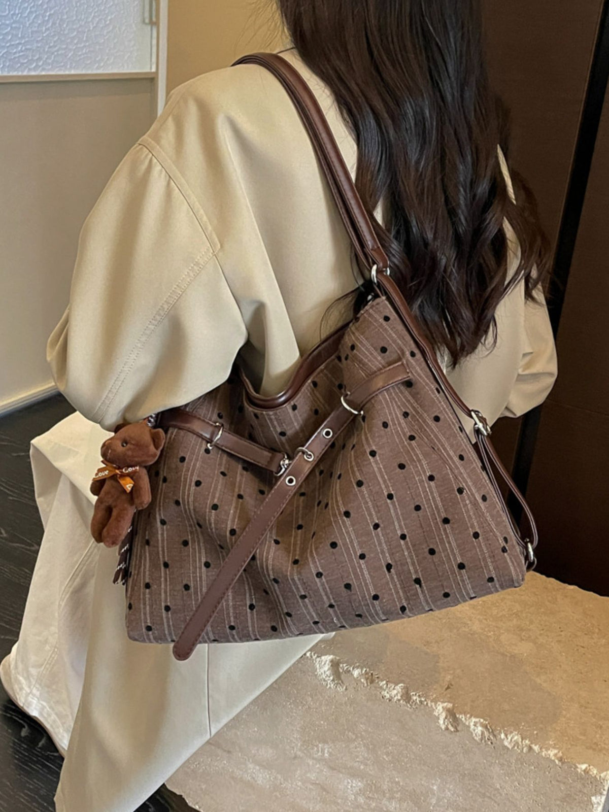 brown handbag featuring buckle straps and polka dot, striped