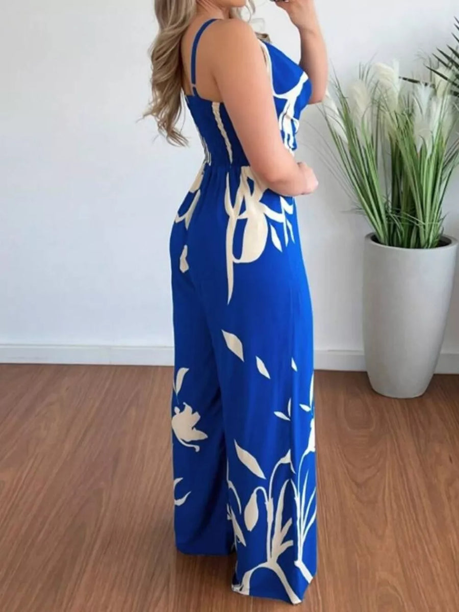 Royal blue abstract leaf print wide-leg jumpsuit with cinched waist and adjustable straps.