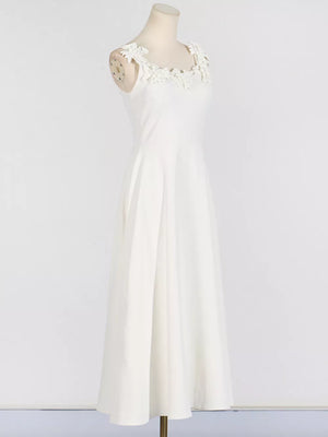 White sleeveless maxi dress with floral applique neckline and A-line skirt.
