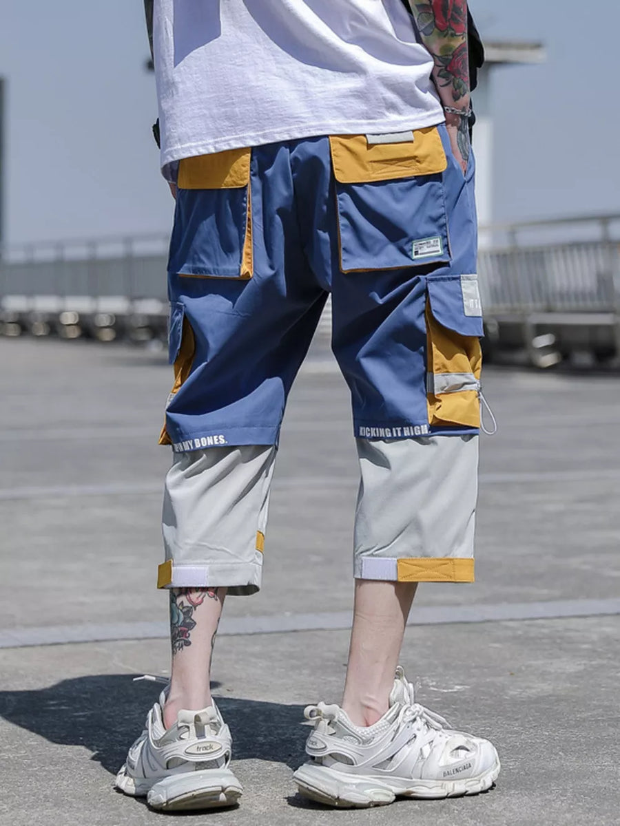 Color block utility cargo pants in blue, yellow, and grey with multiple pockets and text detail.