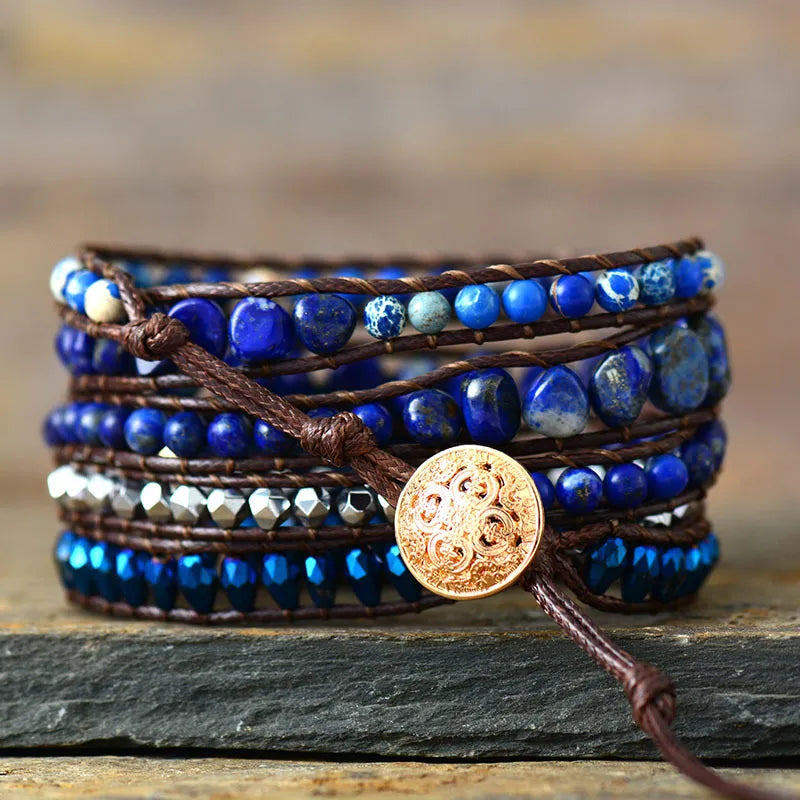 Bohemian wrap bracelet with blue stones and beads on brown cord, featuring a gold button closure.