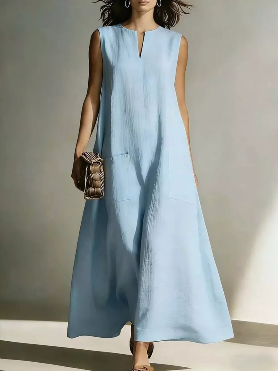 Light blue sleeveless maxi dress with V-neck and pockets, styled with a woven bag.