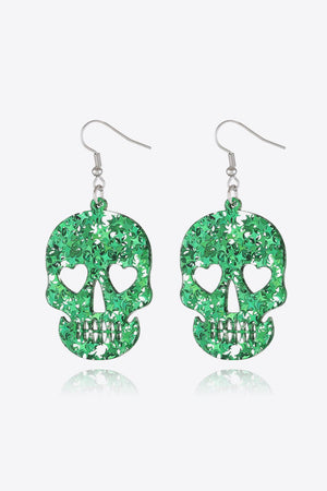 Green glitter skull earrings with heart eye cutouts and starburst pattern.