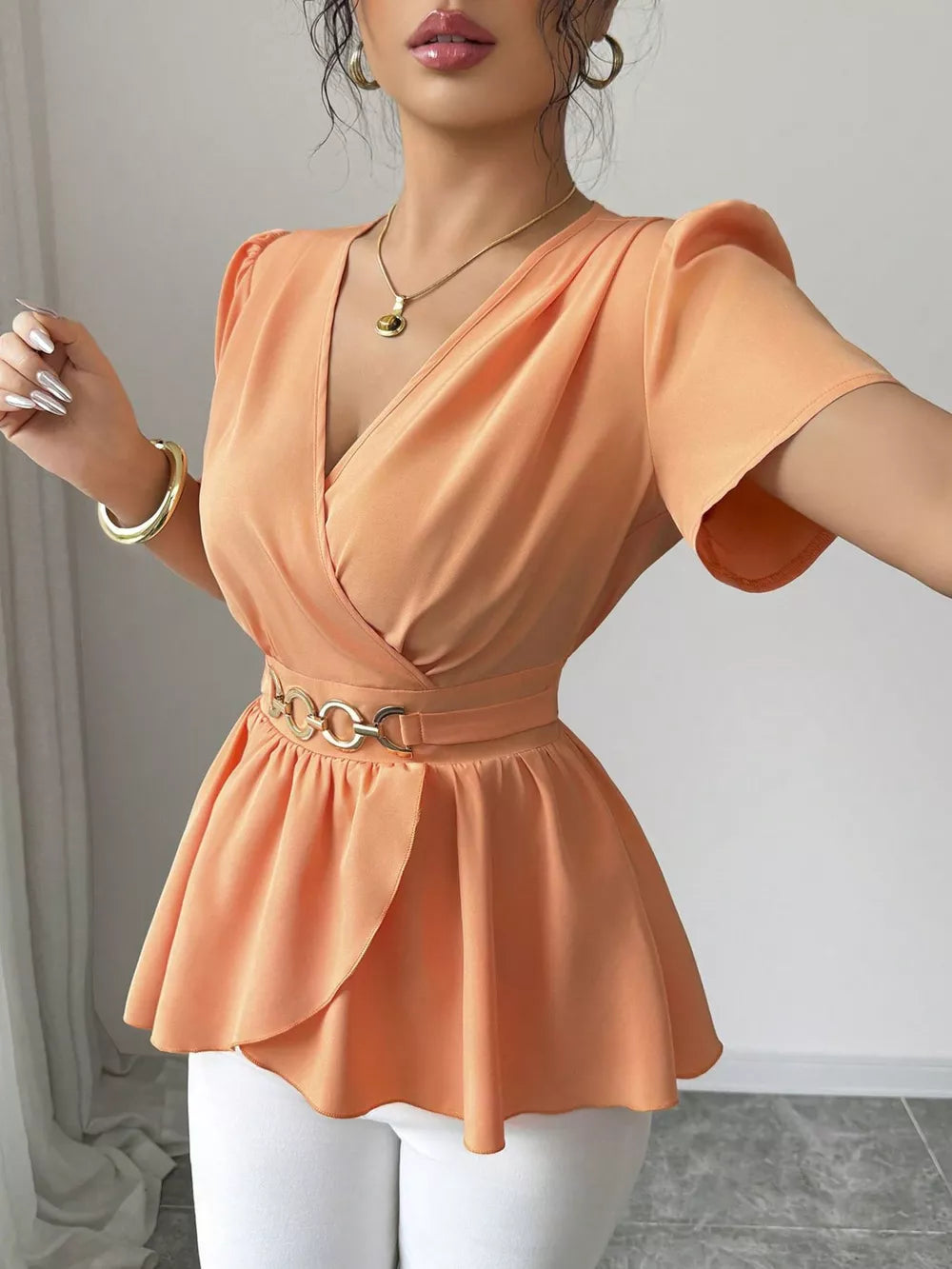 Orange surplice blouse with belted waist and peplum hem.