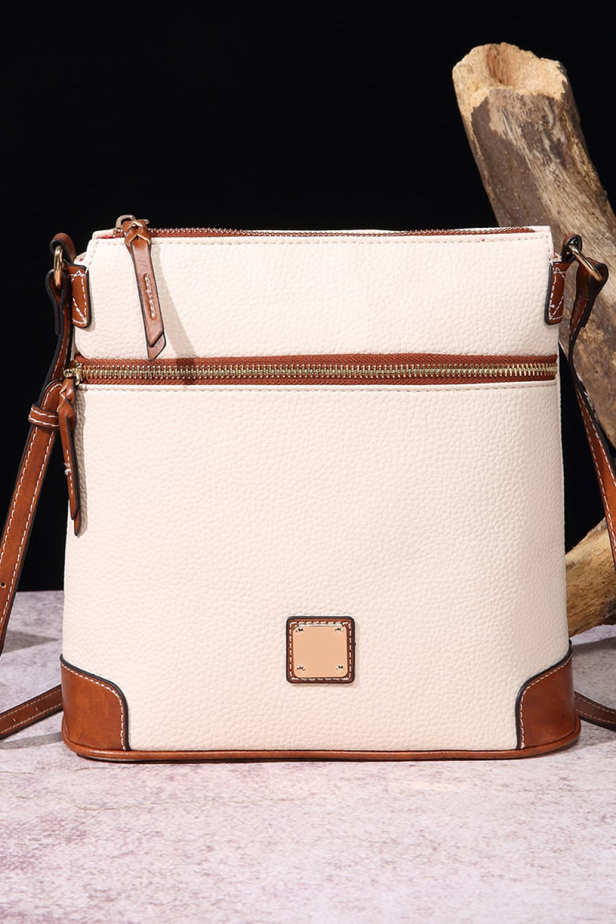 Ivory leather crossbody bag with brown trim and two zip pockets.