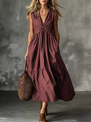 Maxi dress in rust with a knotted V-neck, sleeveless, tiered skirt, and pockets.
