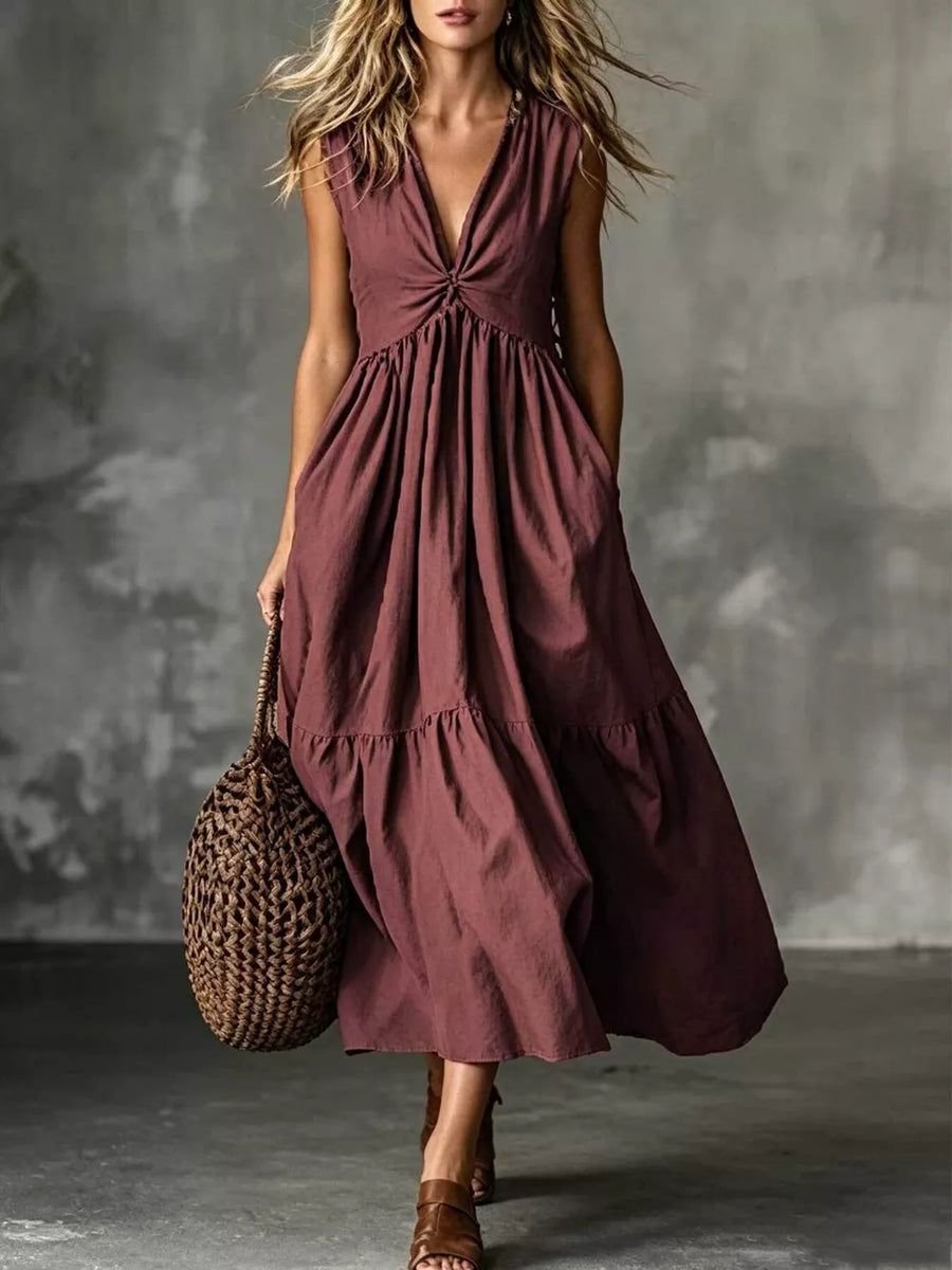 Maxi dress in rust with a knotted V-neck, sleeveless, tiered skirt, and pockets.