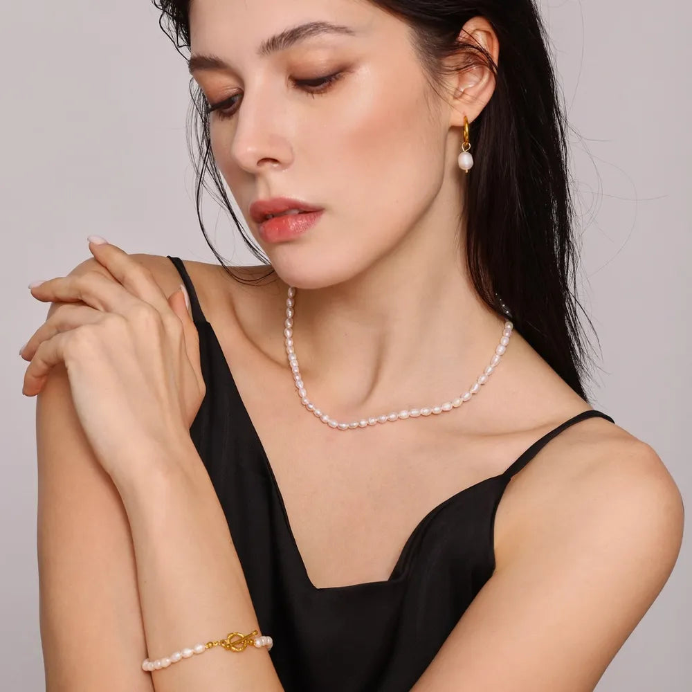 Gold pearl jewelry set with necklace, bracelet, and earrings.