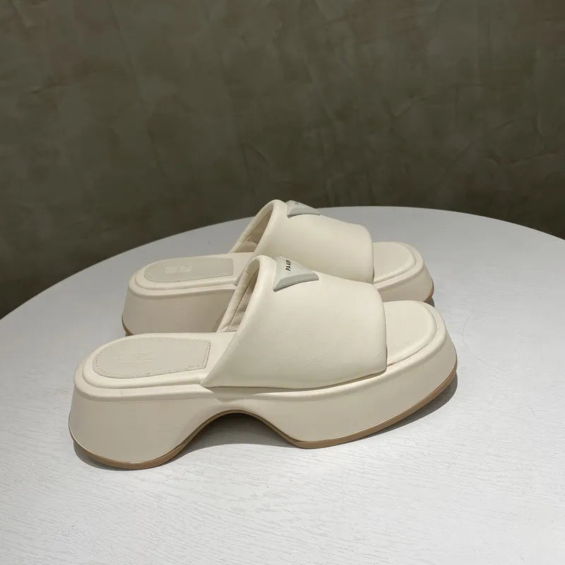 Ivory geometric platform slides with branding detail and thick sole.