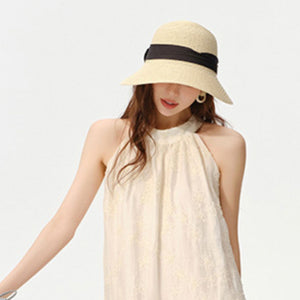 Beige woven straw wide brim sun hat with black ribbon detail.