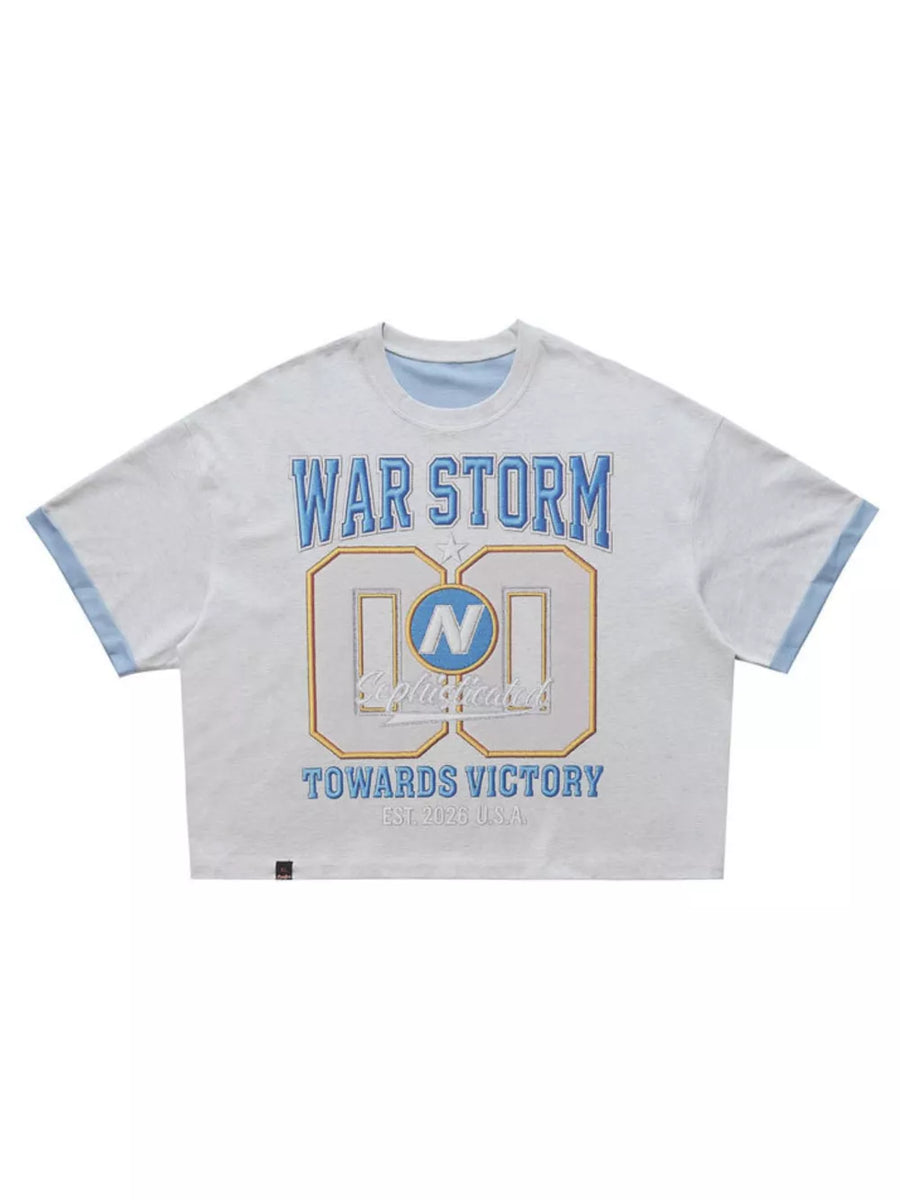 Graphic tee with text "WAR STORM" and "TOWARDS VICTORY" in blue and gold on heather grey cotton.