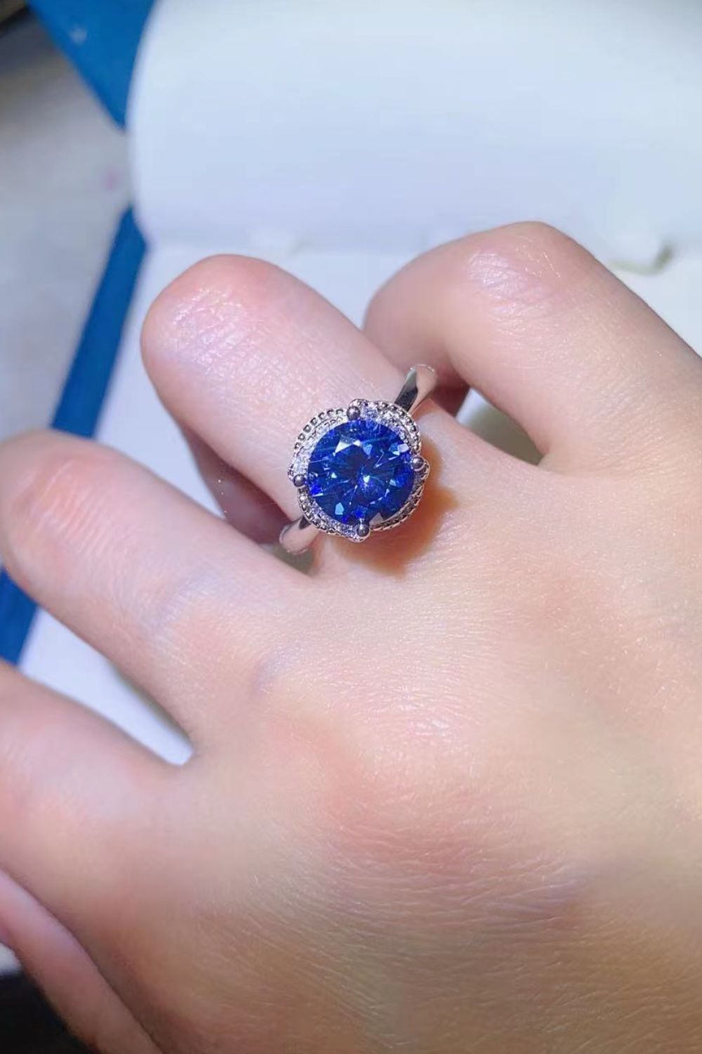 Blue moissanite cocktail ring with a diamond halo and silver band.