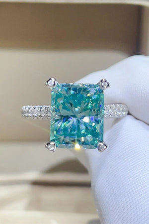 Radiant cut teal pave ring with diamond band and four prong setting.