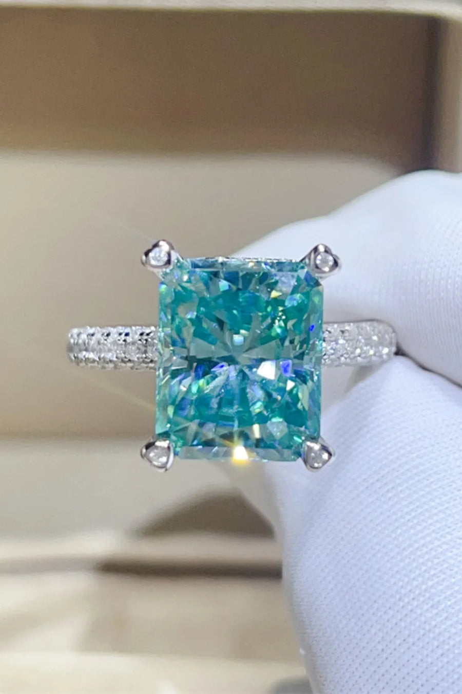 Radiant cut teal pave ring with diamond band and four prong setting.