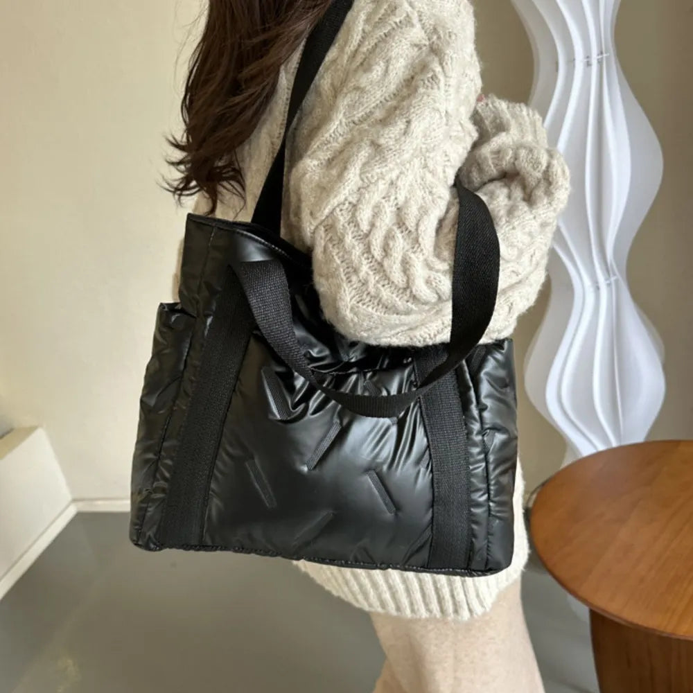 Black padded nylon tote bag with exterior pockets and diagonal stitch detail.