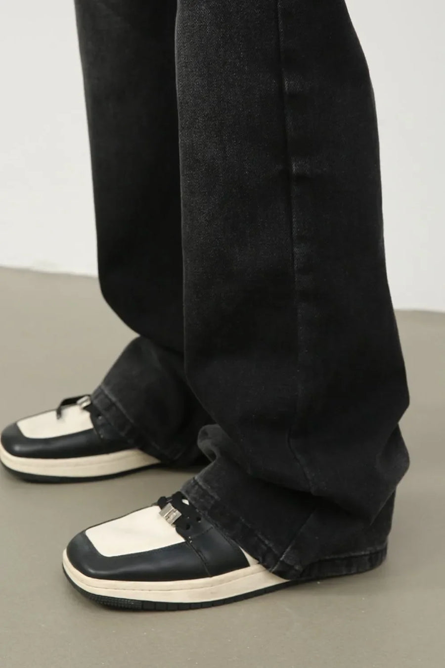 Dark wash denim trousers with exaggerated flare, styled with two-tone sneakers.