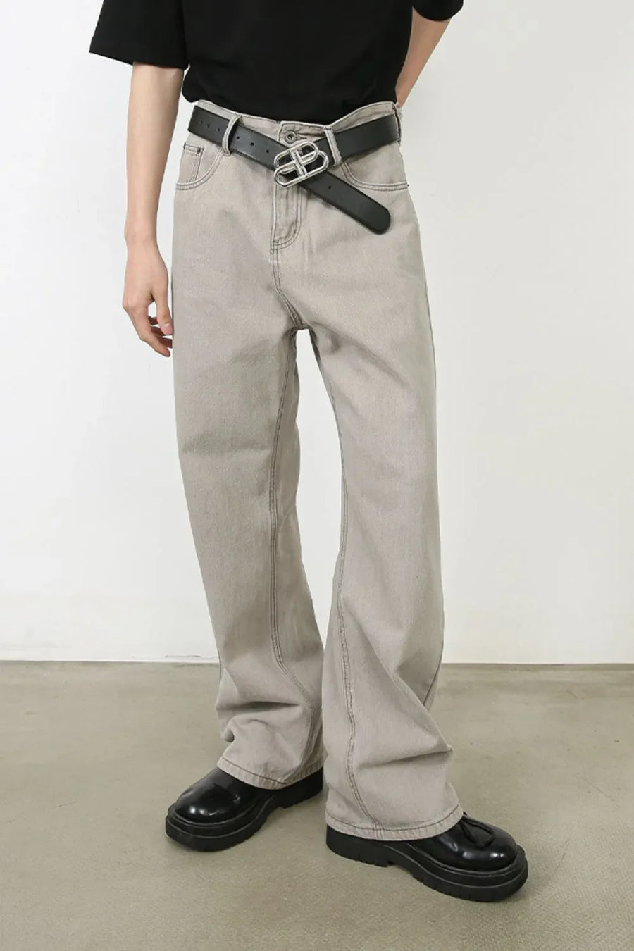 Gray wide-leg denim trousers with seam detail and a black belt.
