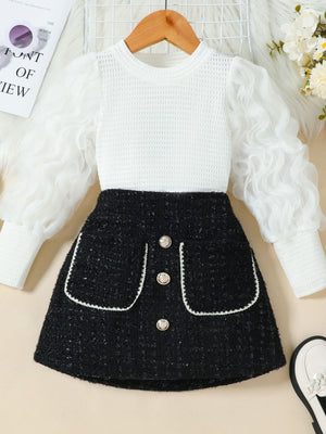 Children's white textured top with sheer ruffled sleeves and black tweed skirt with decorative buttons.
