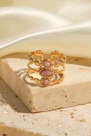 Gold triple stone openwork ring with pink stones and textured bands.