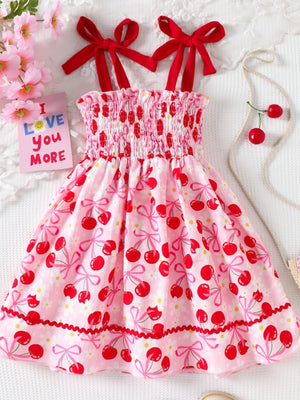 Pink cherry print smocked toddler dress with red bow straps and ruffled hem.