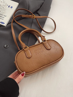 Brown oval pu leather crossbody bag with embossed logo and adjustable strap