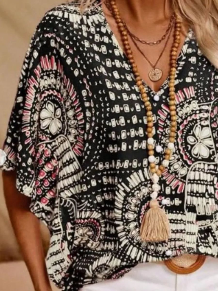 Bohemian print V-neck t-shirt in black with short sleeves and a tassel necklace.