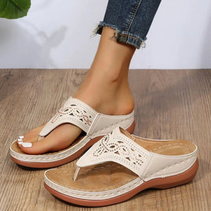 White laser-cut thong sandals with architectural detail and a cushioned sole.