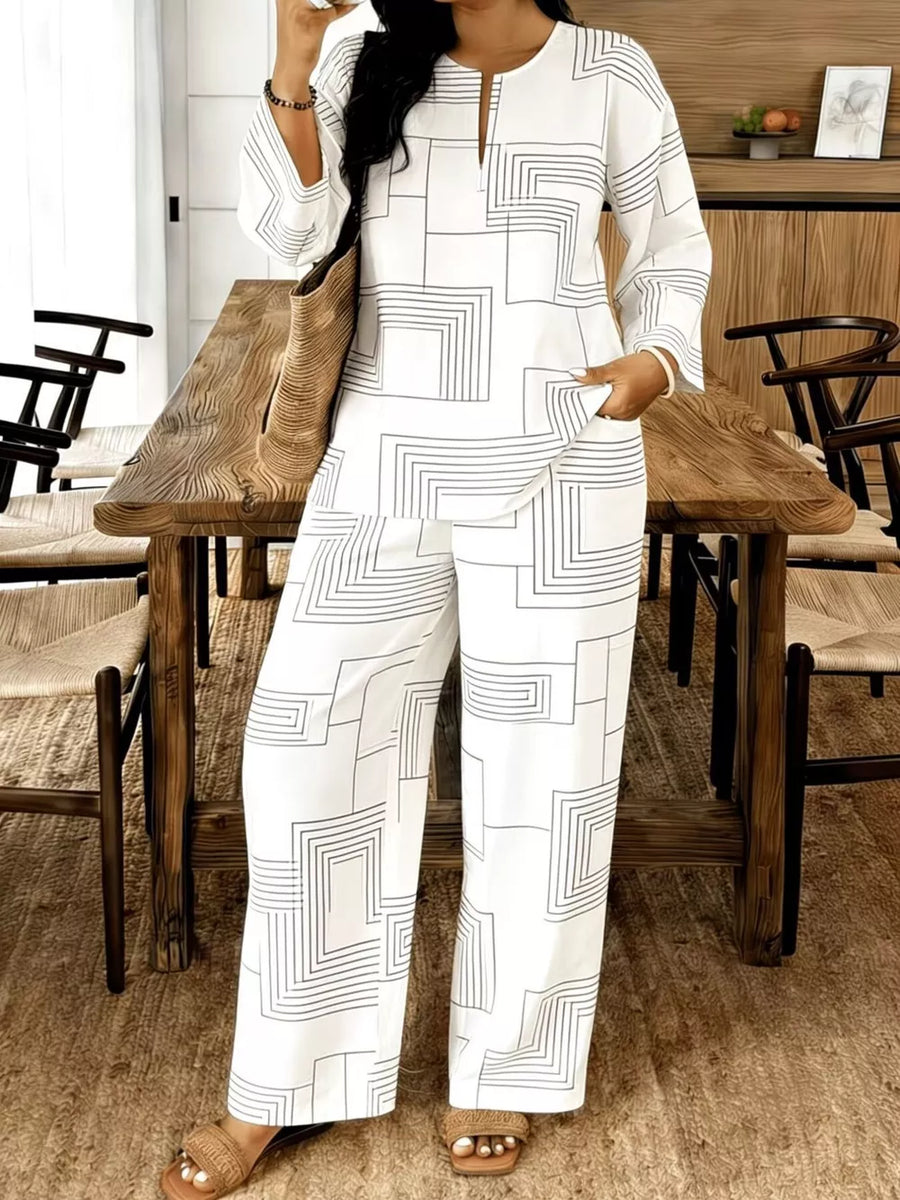 White geometric print pantsuit with V-neck, long sleeves, and wide leg pants.