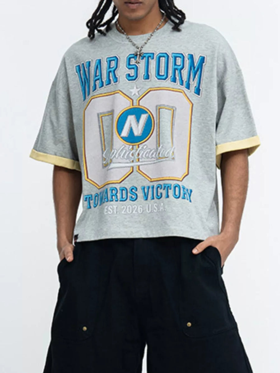 Grey graphic t-shirt with blue and yellow text, crew neck, short sleeves, and yellow trim.