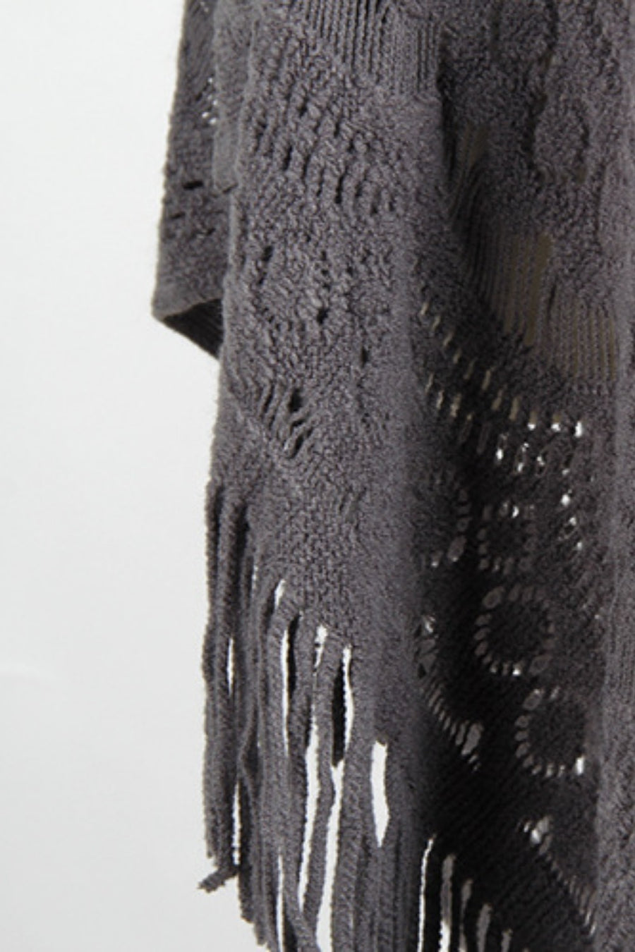 Dark gray crochet poncho with openwork patterns and fringe detail.