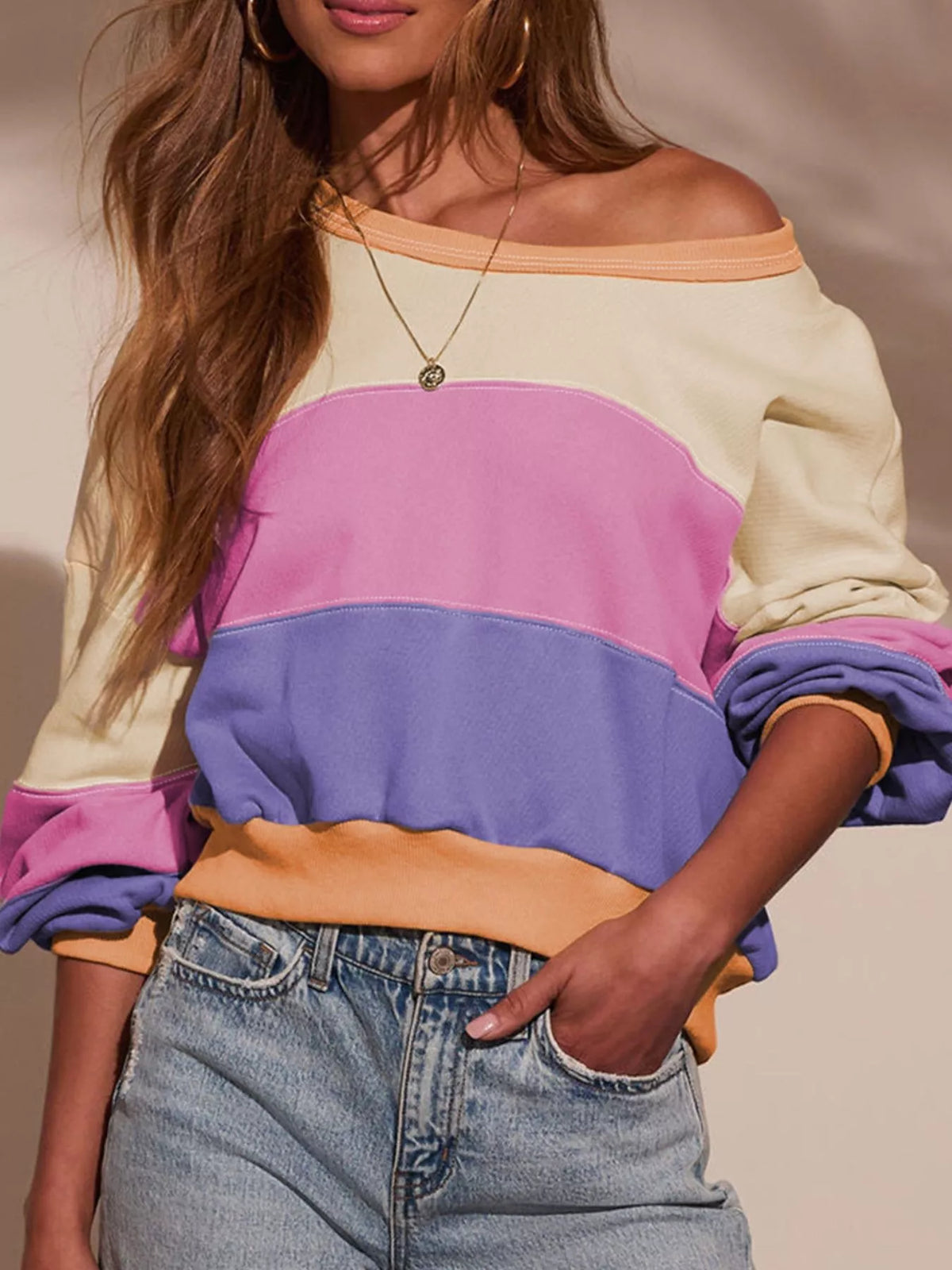 Drop shoulder sweatshirt with colorblock design in cream, pink, purple, and orange.