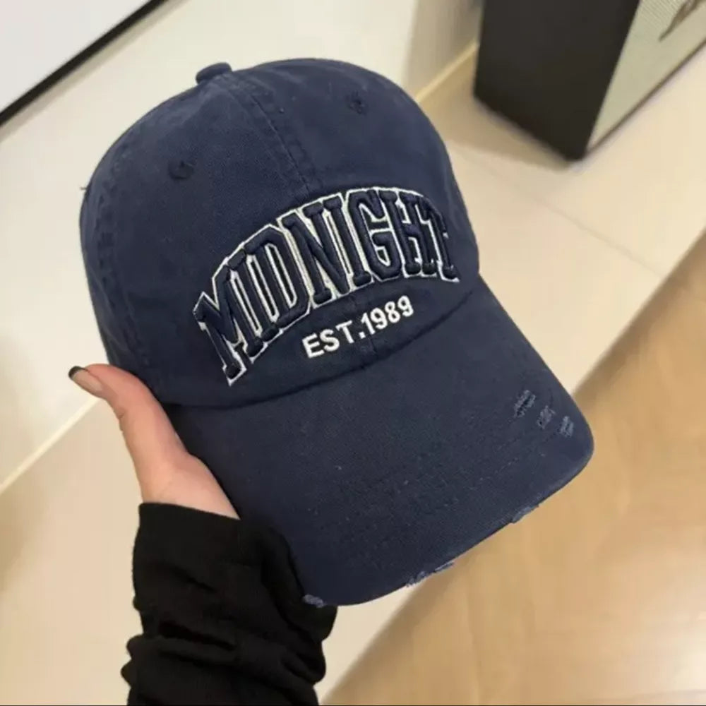 Navy blue distressed baseball cap with white embroidery and frayed details.